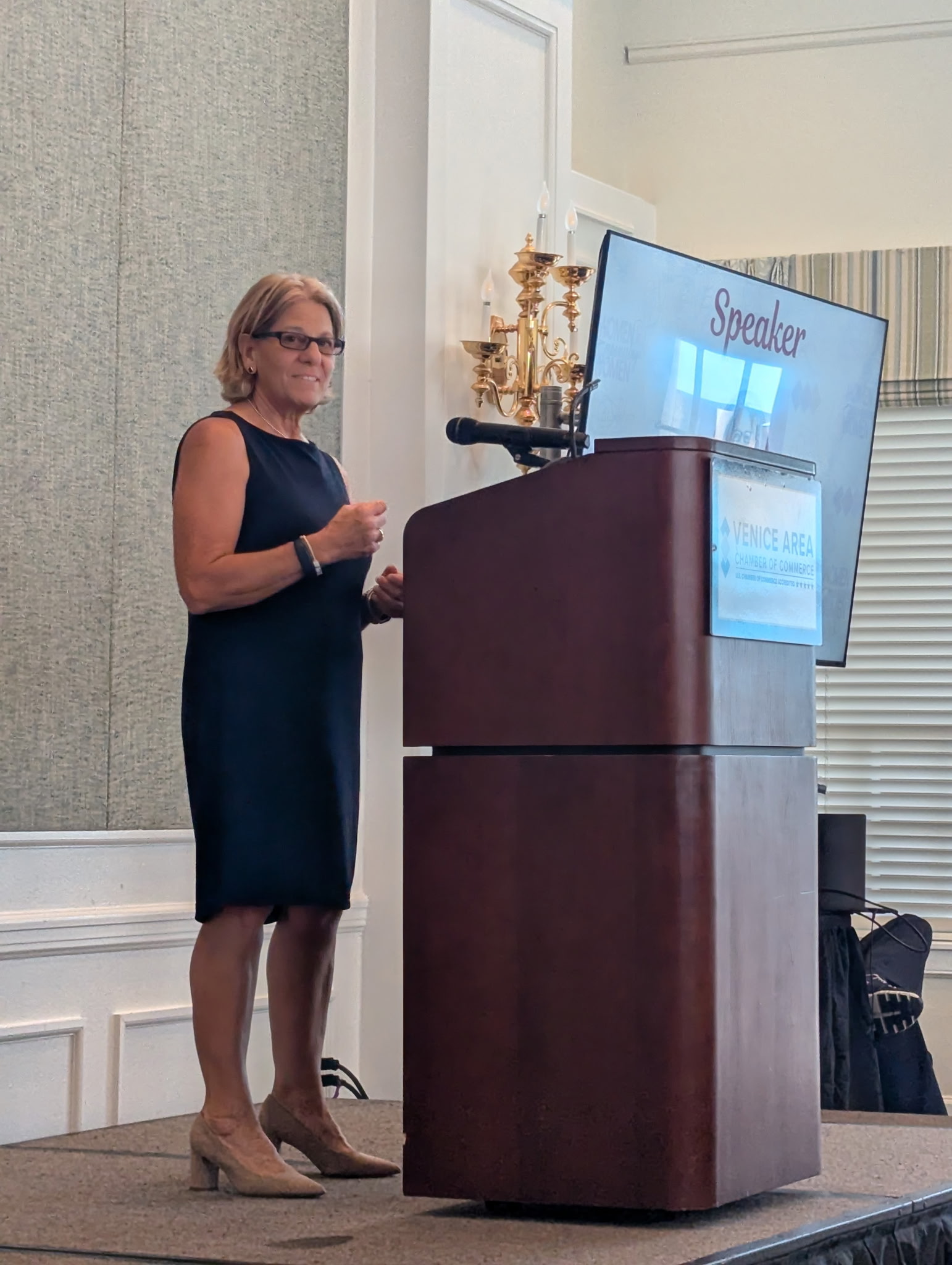 Dr. Joanne Fava speaking at a podium marked Venice Area Chamber of Commerce